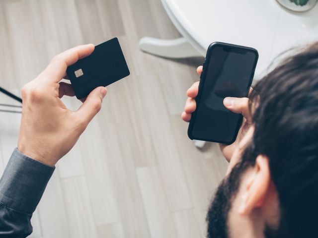 a person holding their phone and a credit card